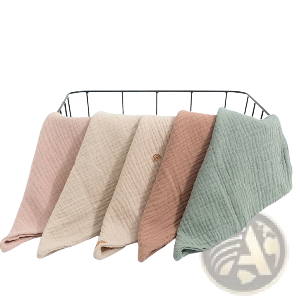 Soft textured organic cotton muslin baby bath towels in pastel pink beige terracotta and sage green neatly folded