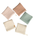 Organic cotton baby bath towel and muslin set in soft pastel colors with subtle ribbed texture and small fabric ties