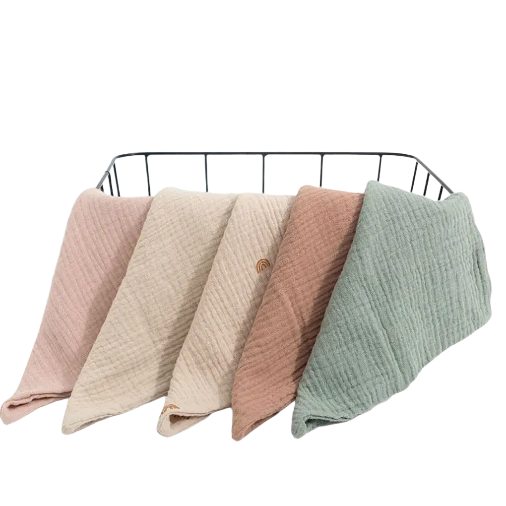 Soft textured organic cotton muslin baby bath towels in pastel pink beige terracotta and sage green neatly folded