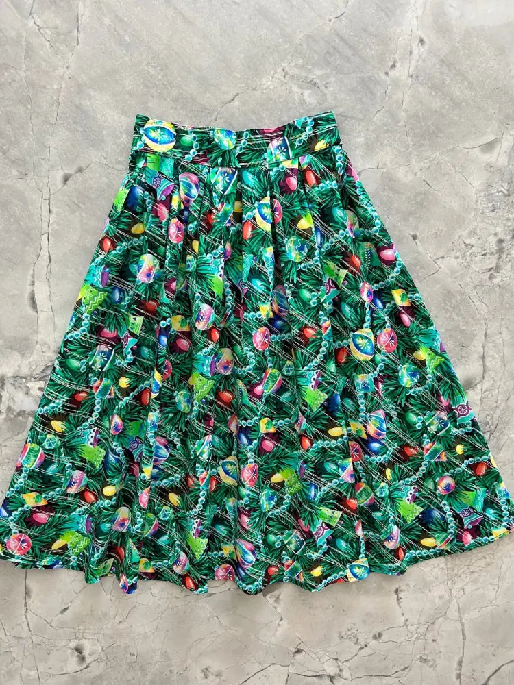 A vibrant green retro holiday pleated skirt with pockets featuring a festive pattern of colorful Christmas ornaments and pine branches