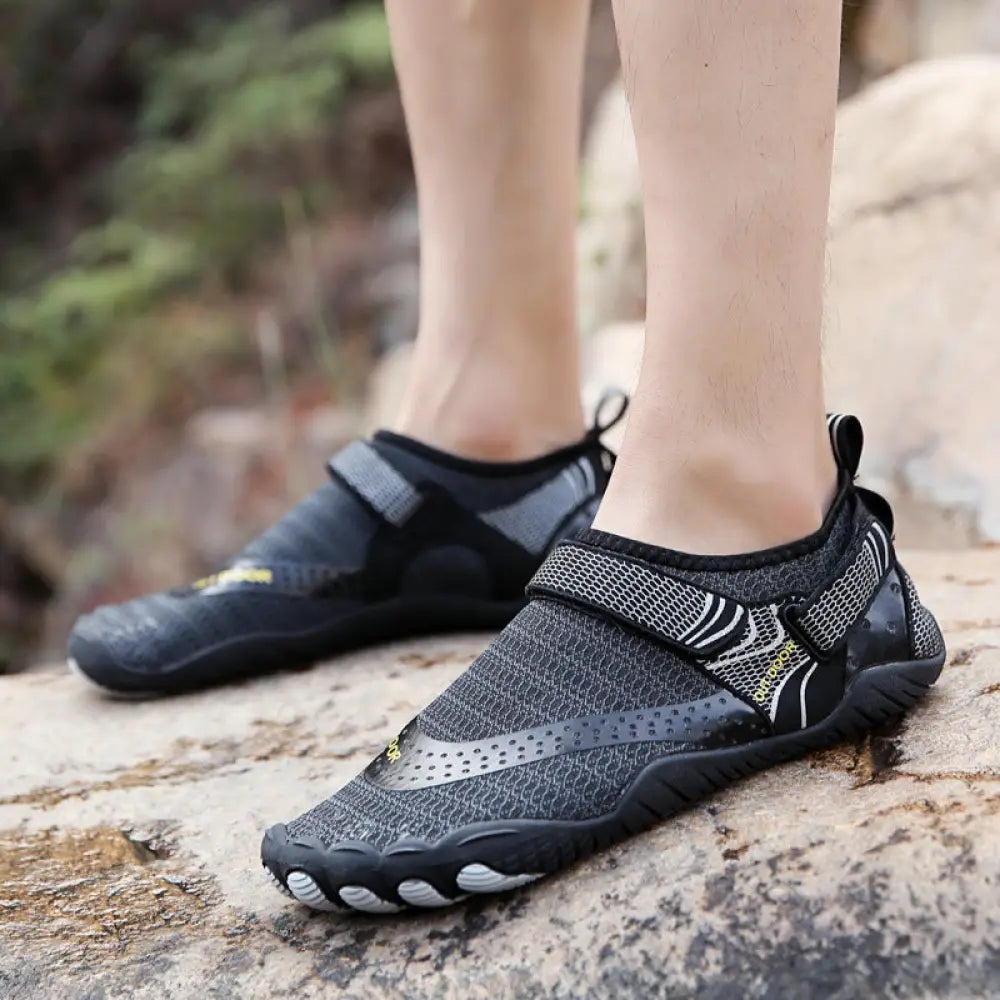 Lightweight cut resistant five finger outdoor wading shoe in black and gray with mesh upper rubber sole and yellow branding