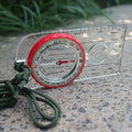 Outdoor navigation compass made of transparent plastic with red dial and green paracord lanyard for hiking
