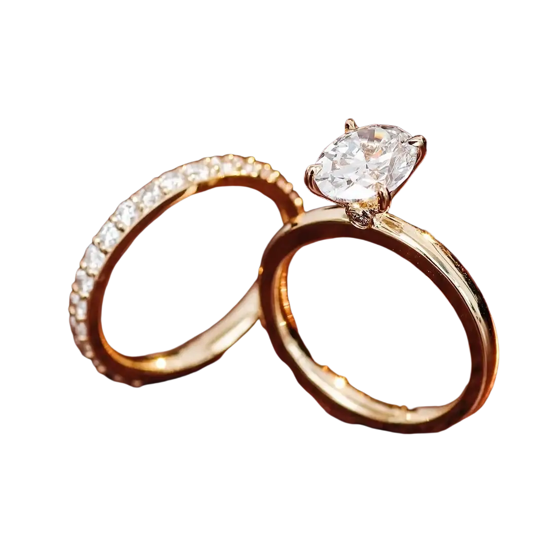 A gold oval lab diamond bridal set featuring an oval-cut diamond ring with four prongs and a diamond-accented band
