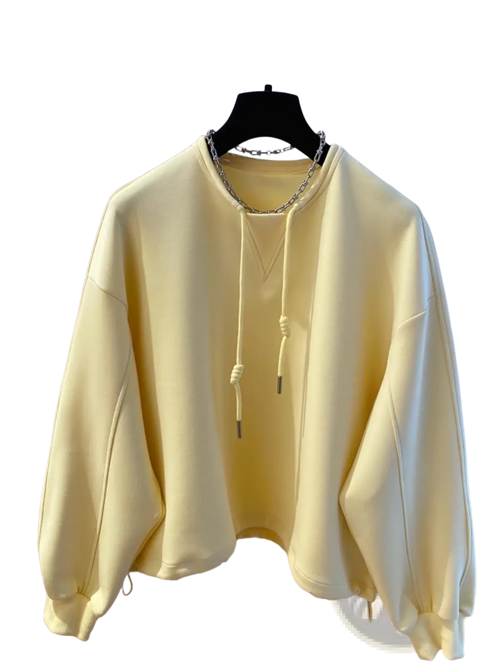 Oversized cream hoodie in soft pale yellow with drawstring hood and silver chain necklace detail visible on front