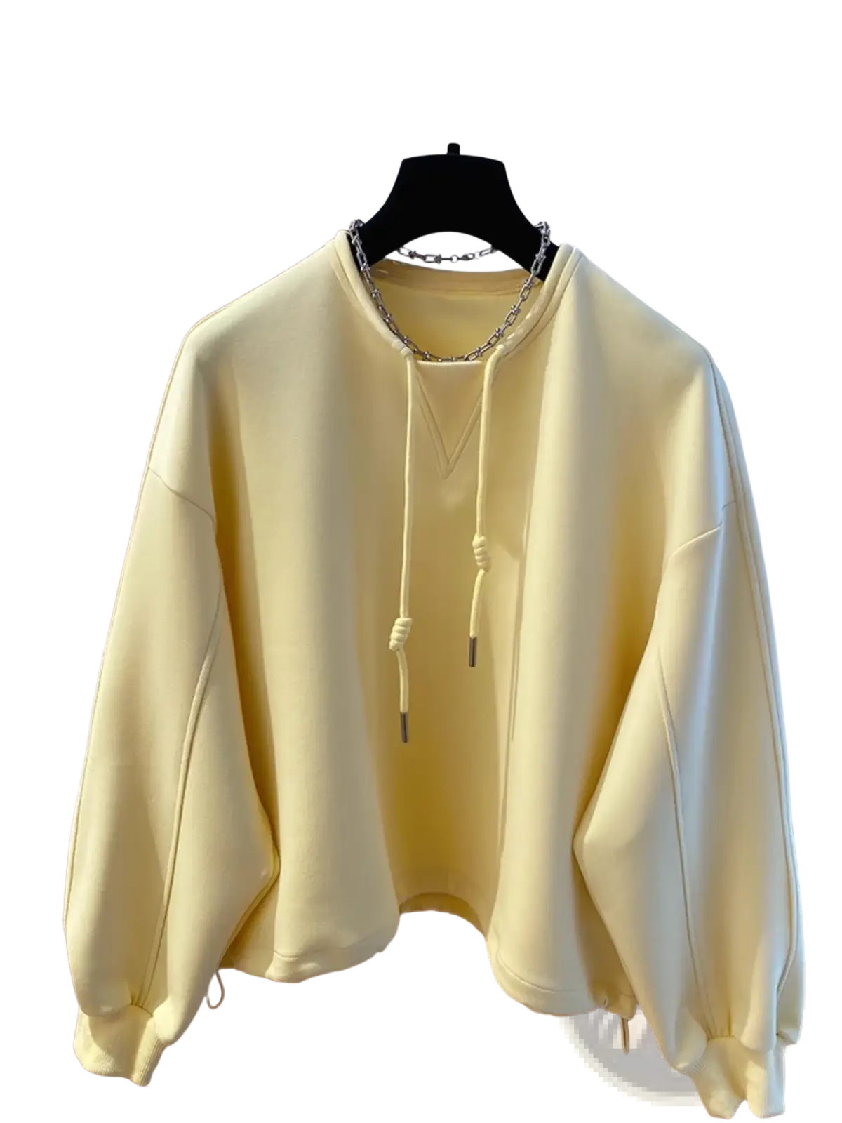 Oversized cream hoodie in soft pale yellow with drawstring hood and silver chain necklace detail visible on front