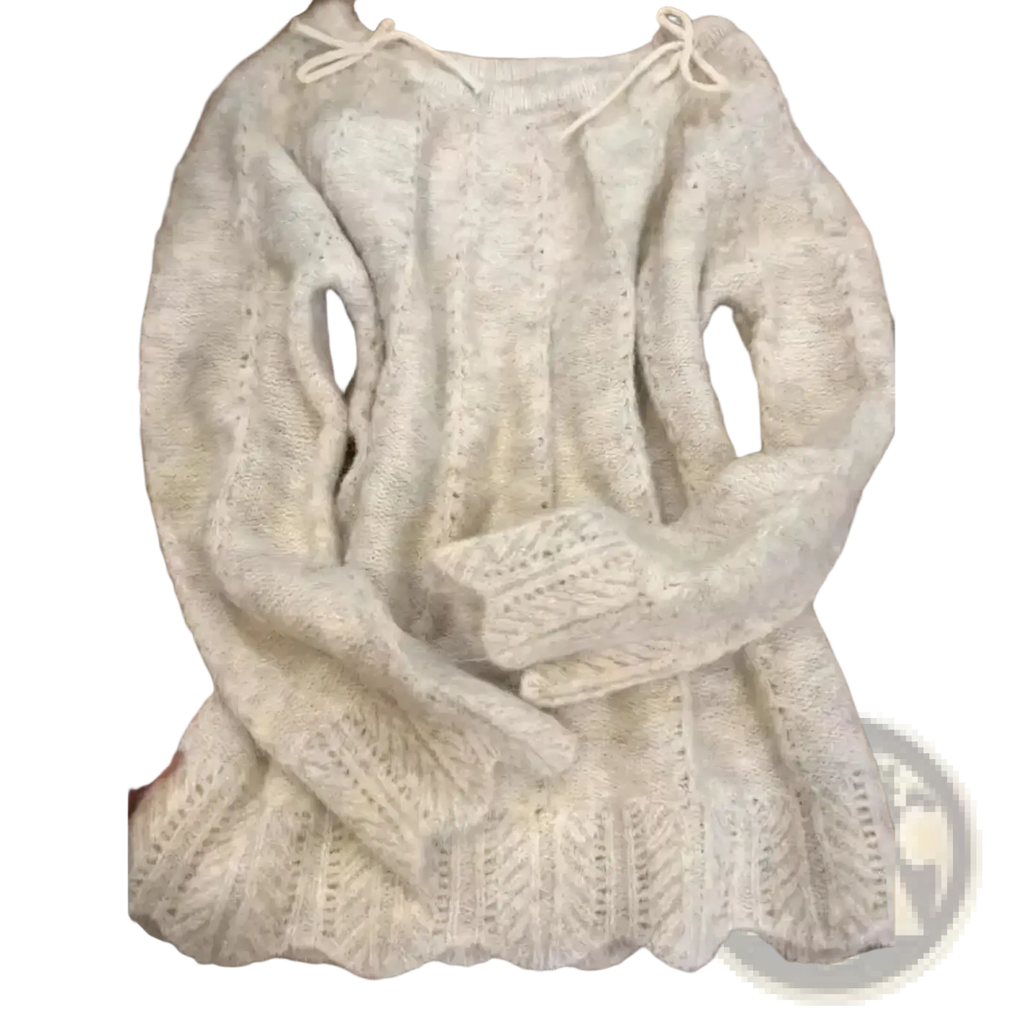 A soft off-white oversized knit sweater with intricate cable and lace patterns and drawstrings at the neckline for winter wear