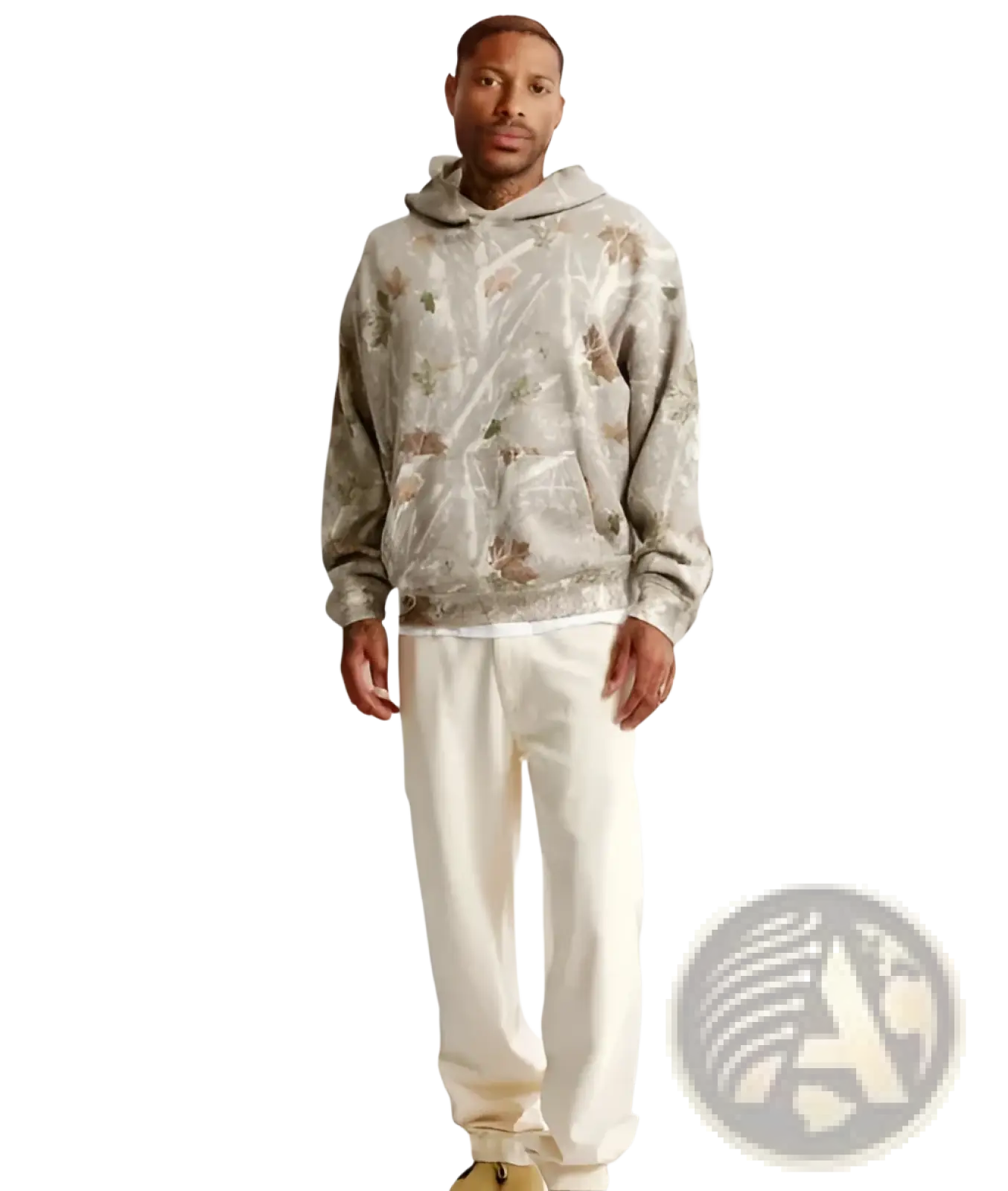 A man wearing an oversized leafy camouflage beige hoodie with subtle floral pattern and matching cream joggers
