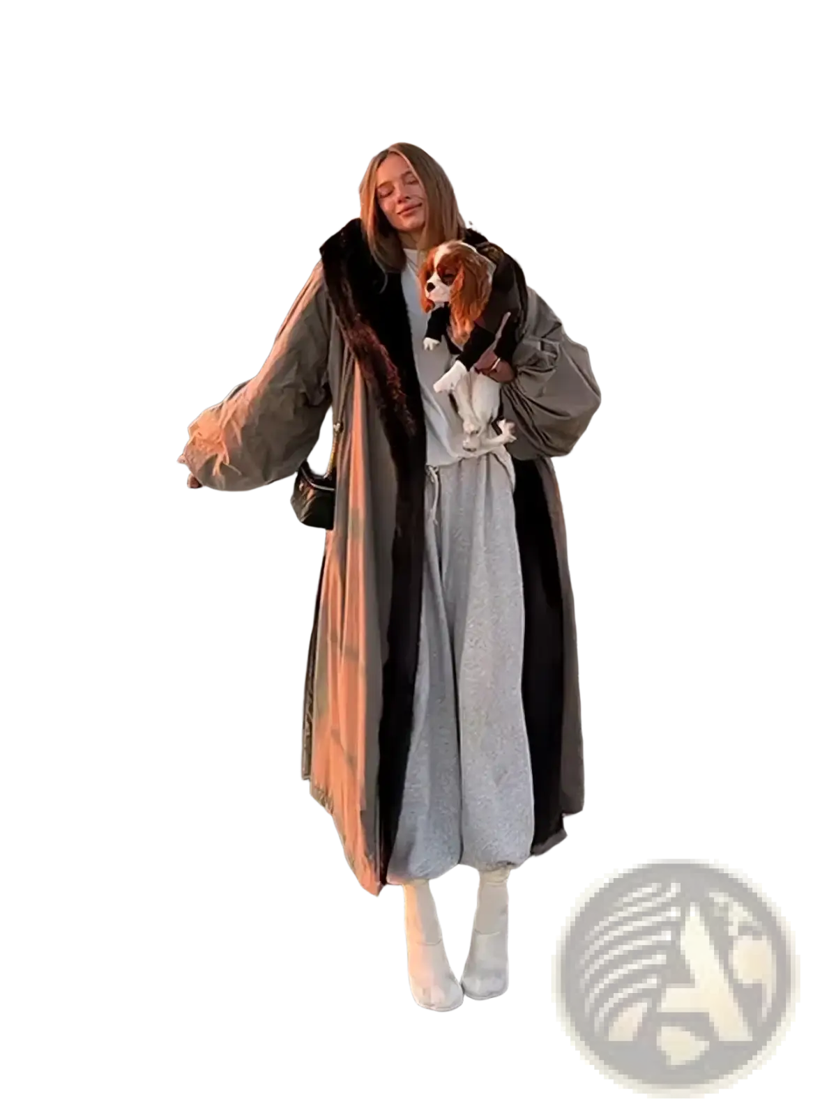 A woman wearing an oversized olive green trench coat with dark fur lined hood and wide leg gray trousers for winter