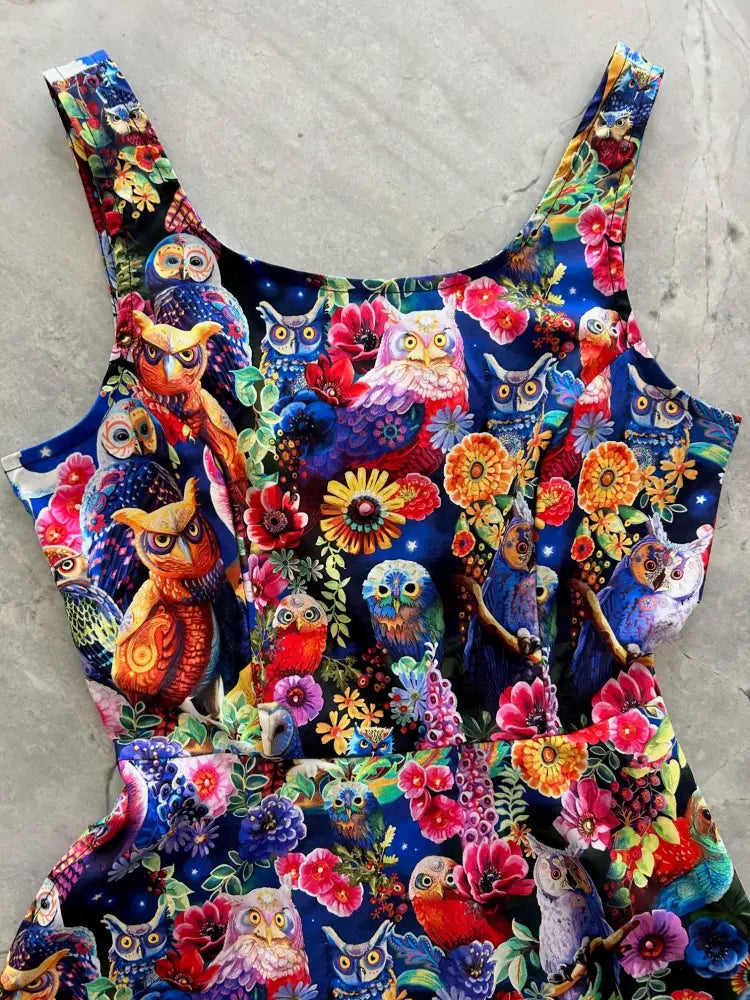 A vibrant owl and floral print sleeveless skater dress with colorful patterns on a deep blue background