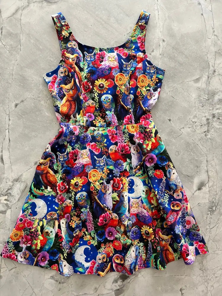 A vibrant sleeveless a-line skater dress with colorful owl and floral print on a deep blue background