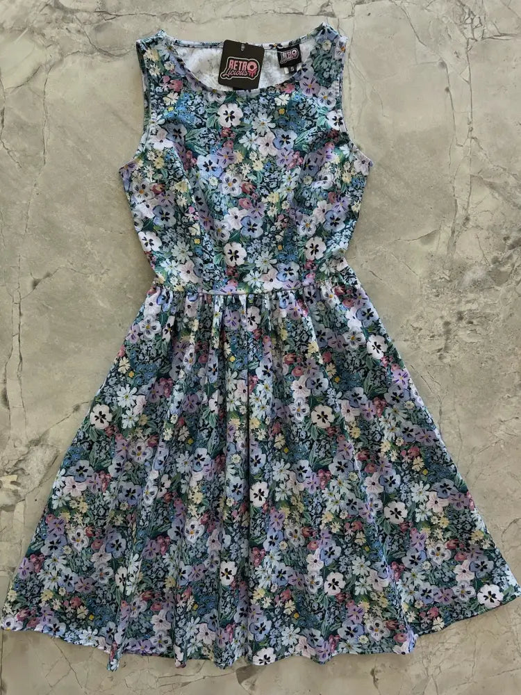 A sleeveless 1950s painted floral cotton a-line midi dress with pockets in pastel lavender pink and white on dark green background