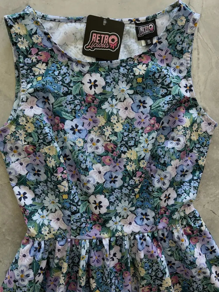 A sleeveless 1950s painted floral cotton a-line midi dress with pockets featuring pastel blossoms on dark green background