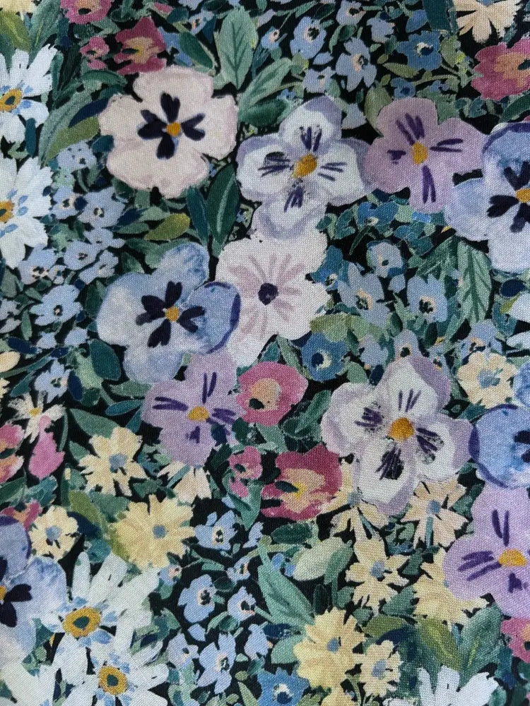 A 1950s painted floral cotton a-line midi dress with pockets featuring pastel pansies and daisies on green leaves