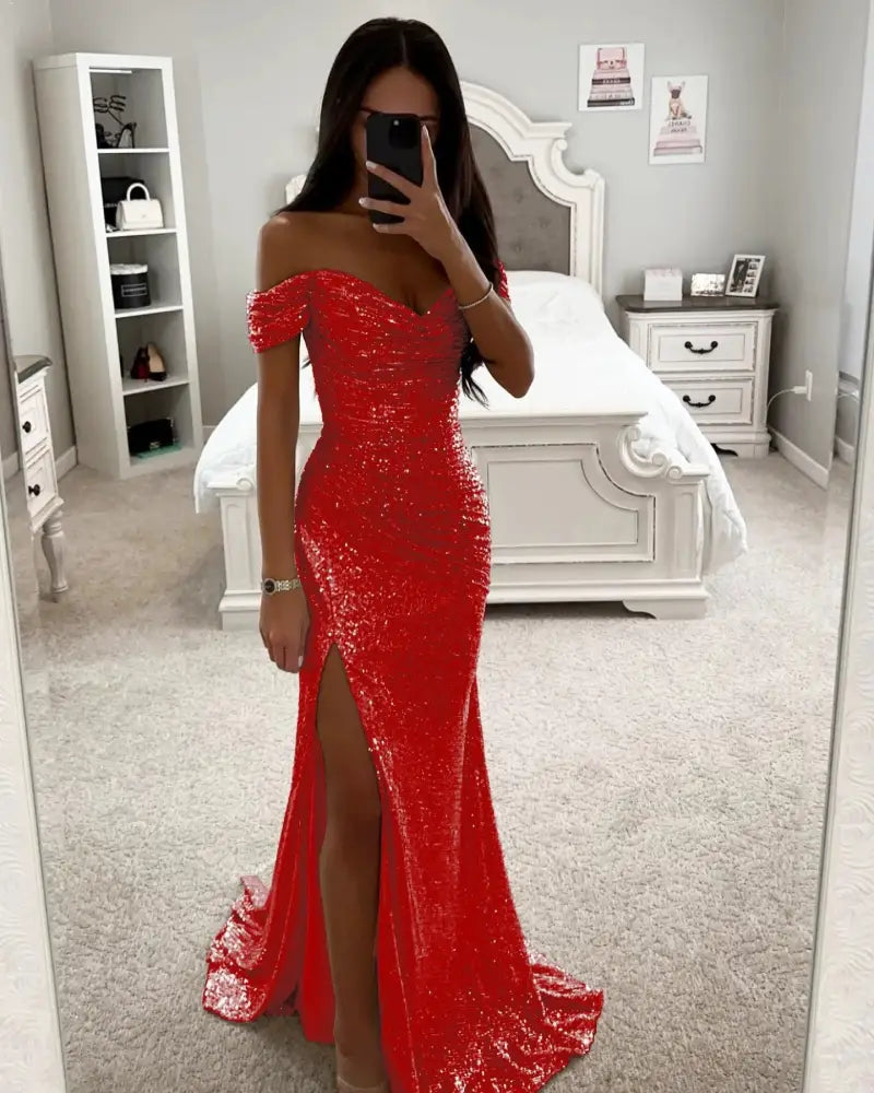 A shimmering red sequined off the shoulder mermaid gown with a high slit and fitted silhouette