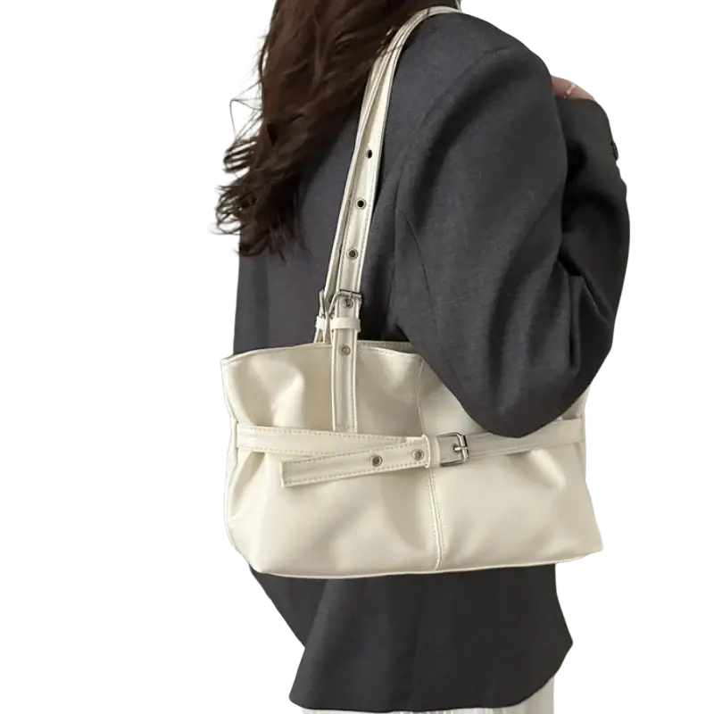 Cream-colored patent leather shoulder bag with structured rectangular shape and adjustable shoulder strap with silver buckle