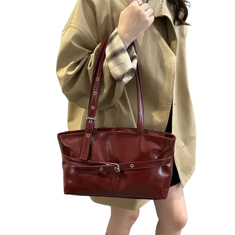 A glossy burgundy patent leather shoulder bag with structured design and adjustable shoulder strap silver hardware accents