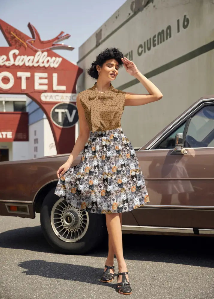 A woman wears a vintage paw print bow sleeveless cotton top in tan polka dot paired with a cat face patterned skirt
