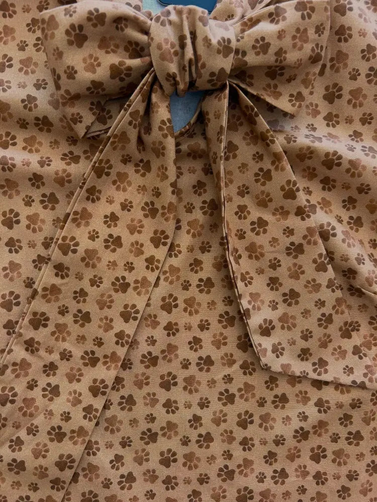 Beige sleeveless cotton top with brown paw print pattern tied into a bow at the top vintage style