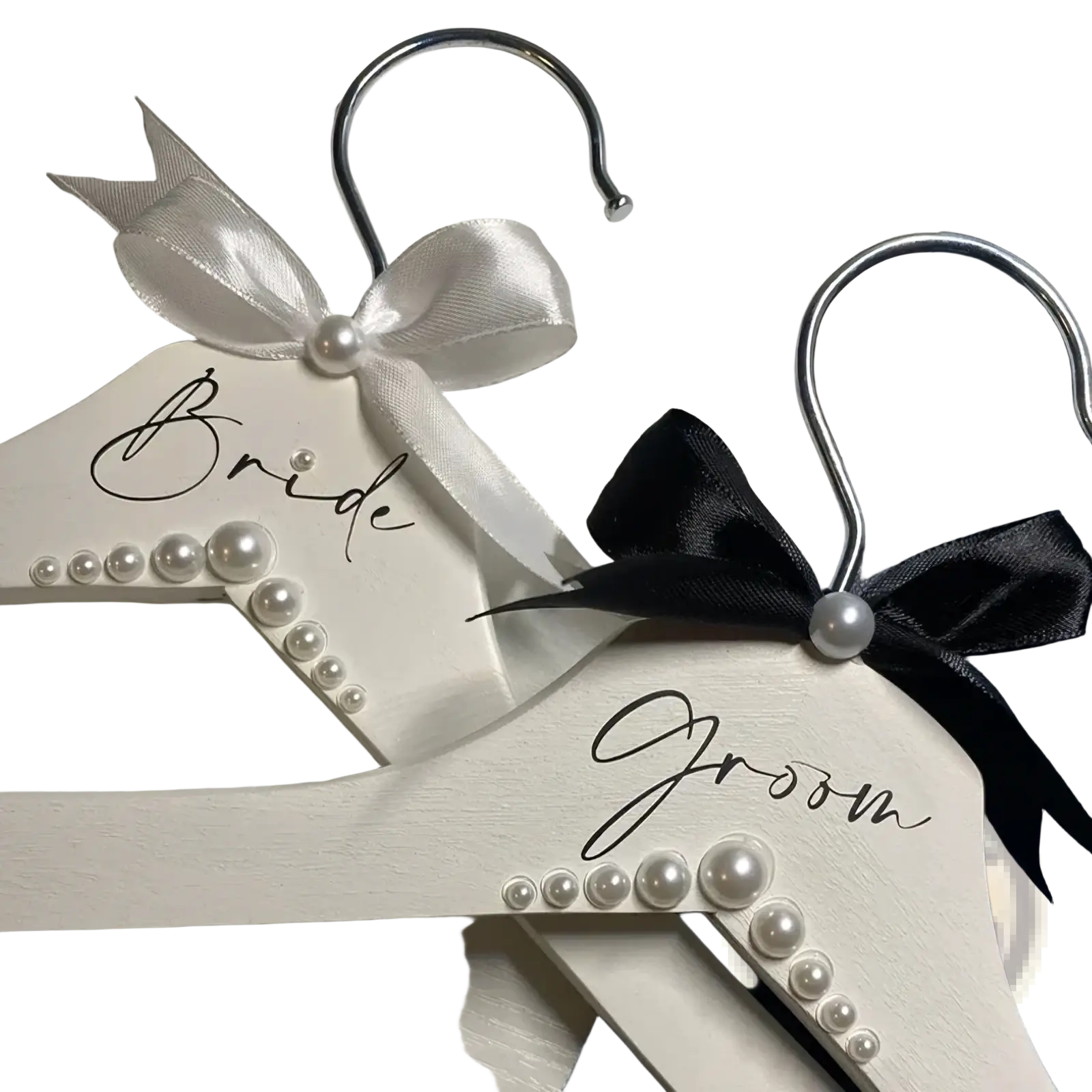 White wooden wedding hangers set with pearls satin bows one labeled bride in black cursive for bride and groom use