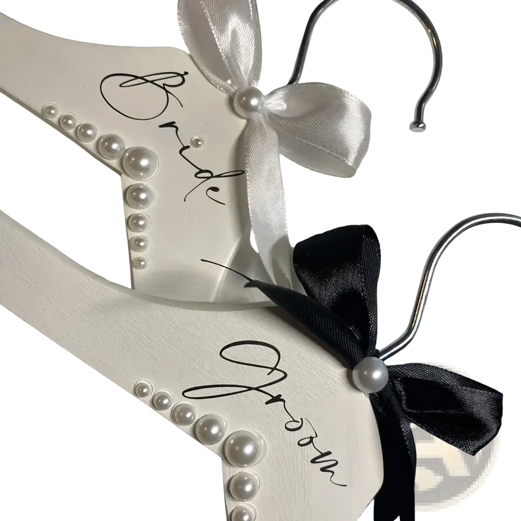 White wooden pearl bride and groom wedding hangers set with satin bows for bridal attire display
