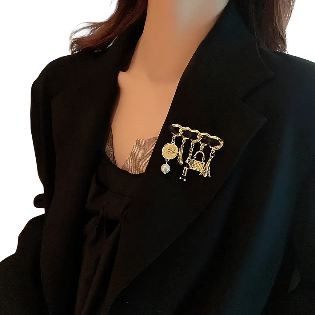 Pearl Flower Number 5 gold brooch pin featuring a gold-toned chain-link design with pearl coin and handbag charms