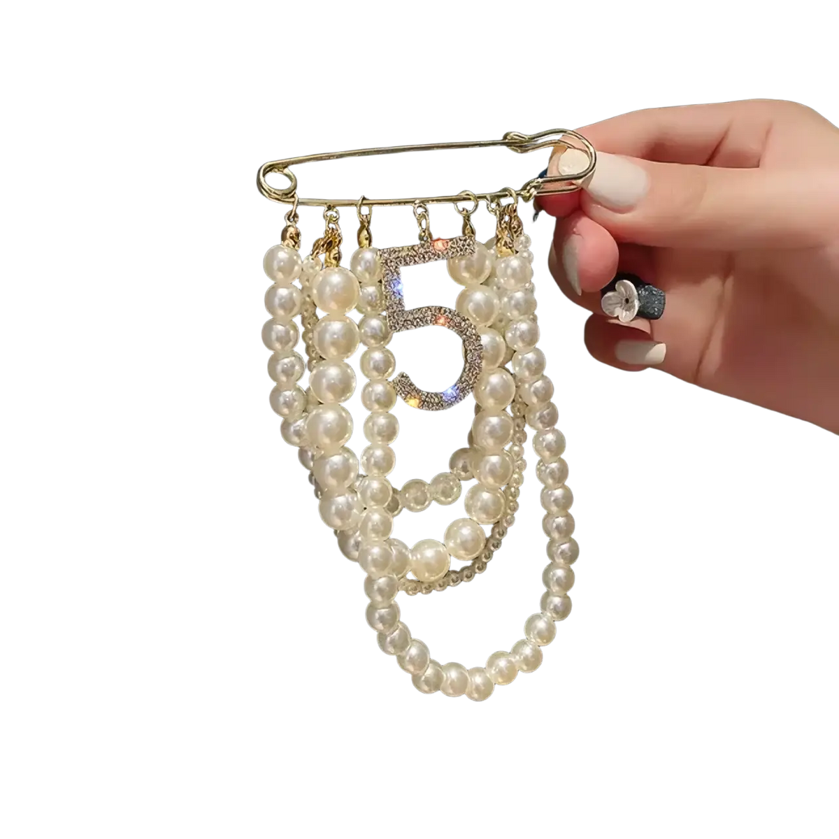 A gold-toned safety pin brooch with white pearl strands and a central sparkling number 5 embellishment