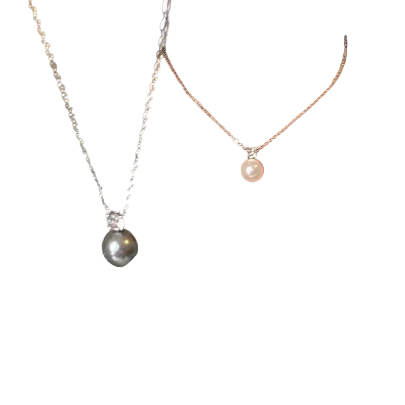 Two delicate silver pearl pendant necklaces with a black pearl and a smaller white pearl on clavicle chains