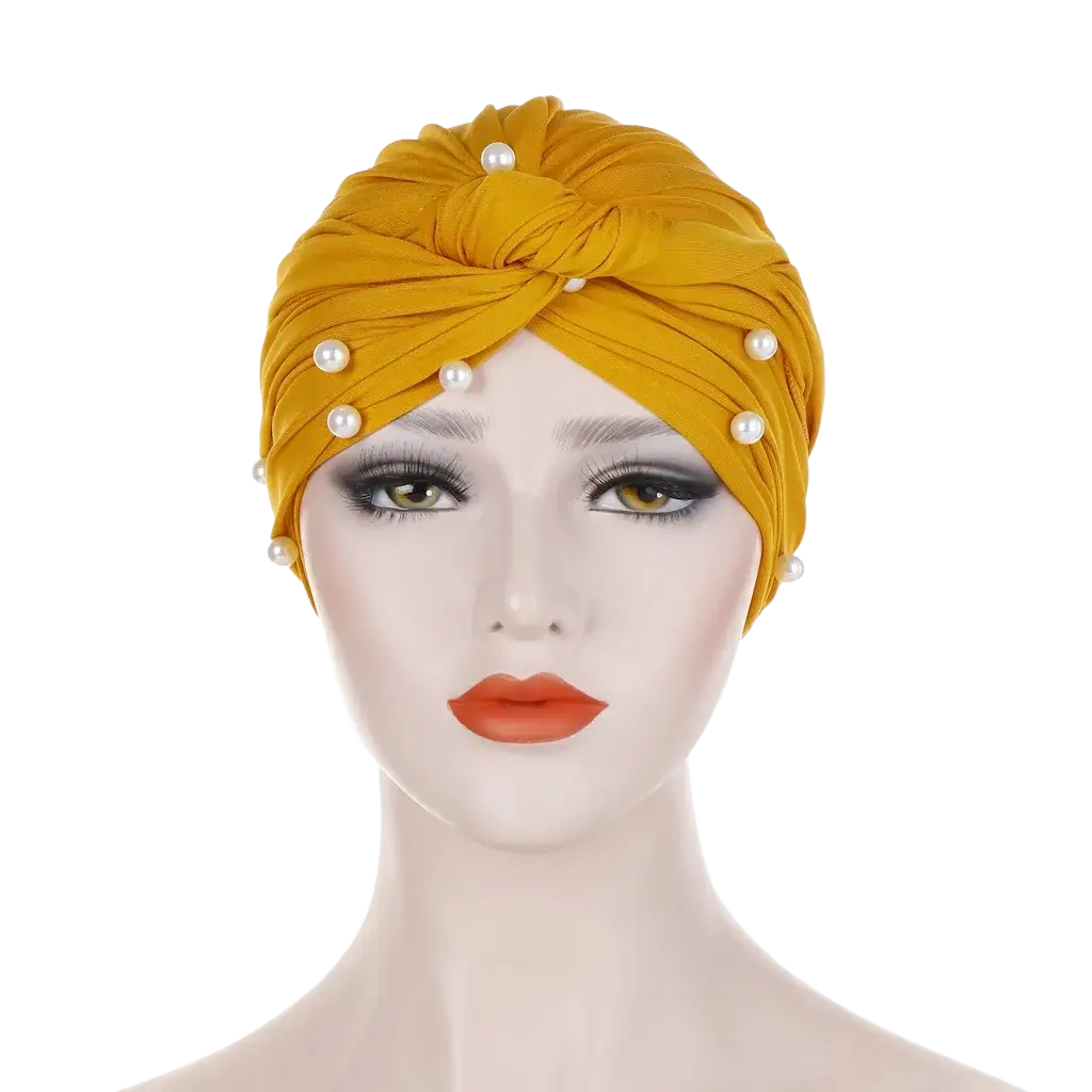 A golden-yellow velvet turban hijab for women adorned with evenly spaced white pearls along its twisted design