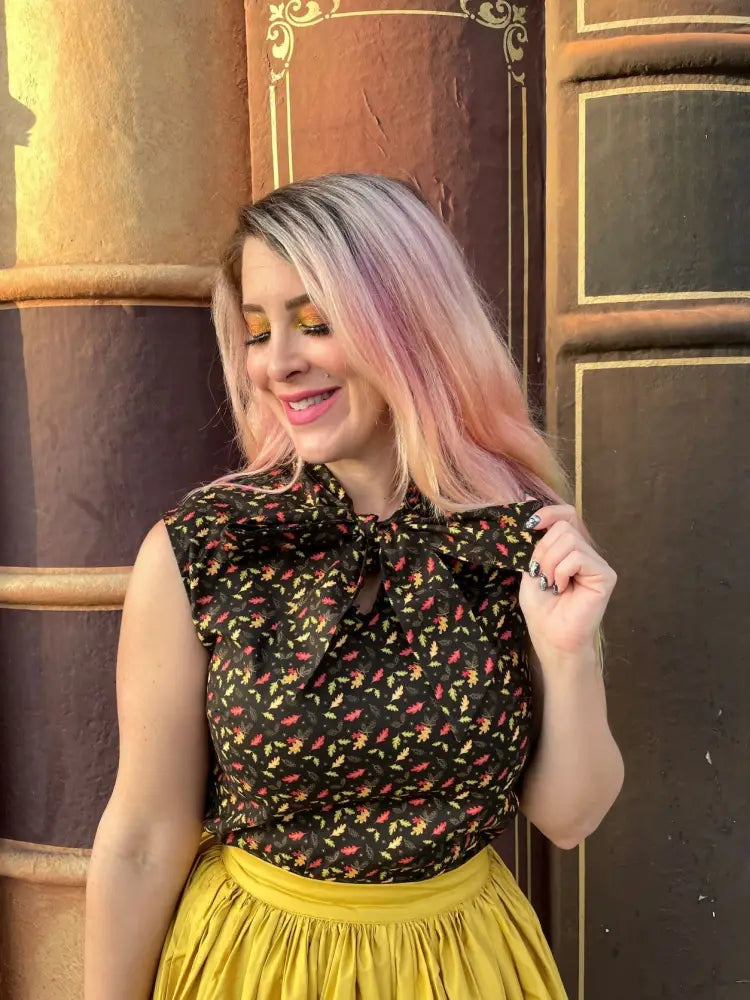 A black floral blouse with a large bow neckline paired with a mustard yellow 1950s cotton swing skirt with pockets