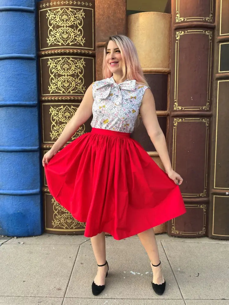 A vibrant red cotton midi swing skirt with full skirt and fitted waistband featuring pockets