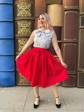 A vibrant red cotton midi swing skirt with full skirt and fitted waistband featuring pockets