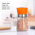 A transparent glass salt grinder with an orange plastic top and silver band filled with pink Himalayan sea salt