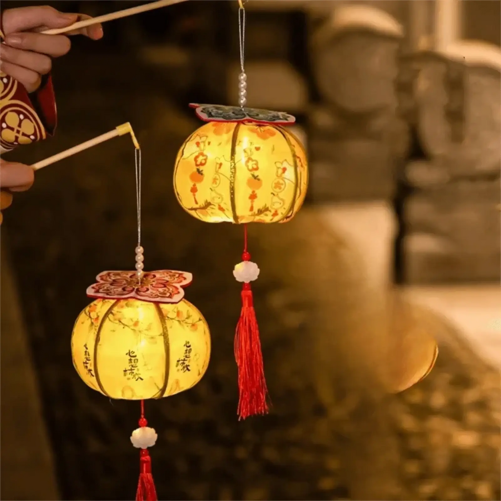Two glowing yellow persimmon lanterns with floral designs and red tassels for chinese new year led decor