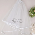 Personalized white tulle bachelorette party veil with black script inscription and satin ribbon trim for bridal shower use