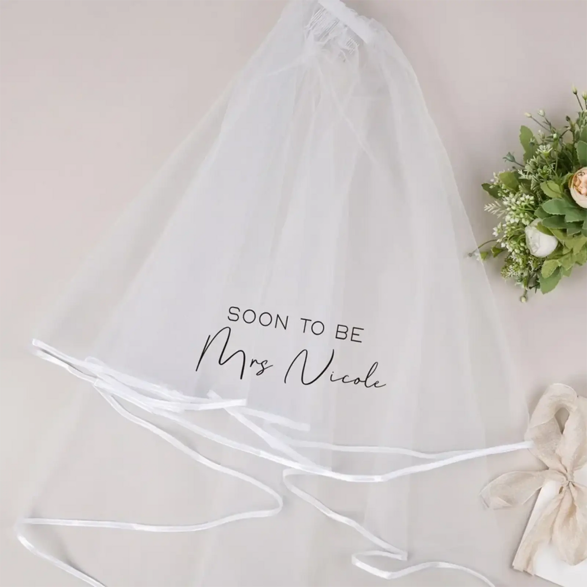 Personalized white tulle bachelorette party veil with black script inscription and satin ribbon trim for bridal shower use