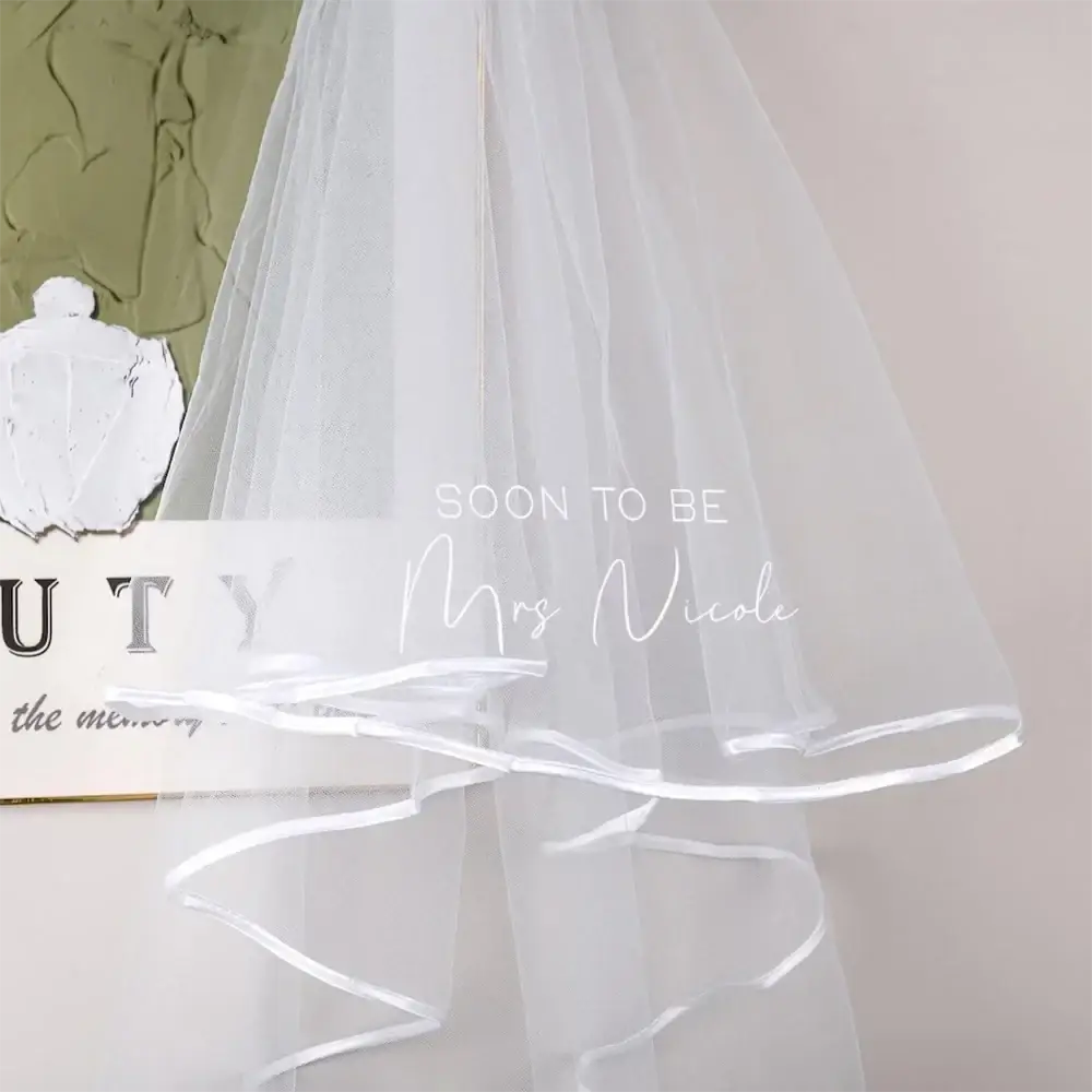 Personalized bachelorette party veil made of delicate white multi-layered tulle with ruffled hem and satin trim