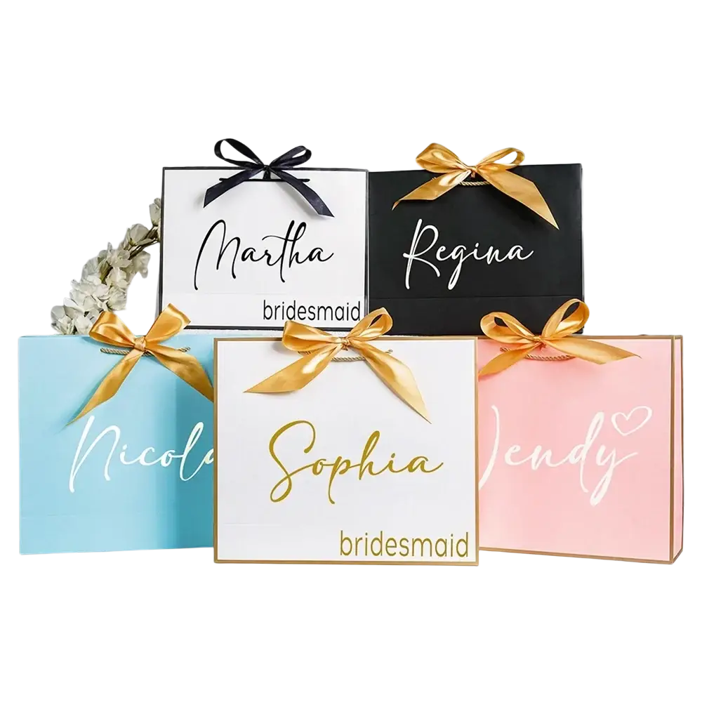 Personalized bridesmaid gift bags in pastel and black with gold and white cursive names tied with satin bows