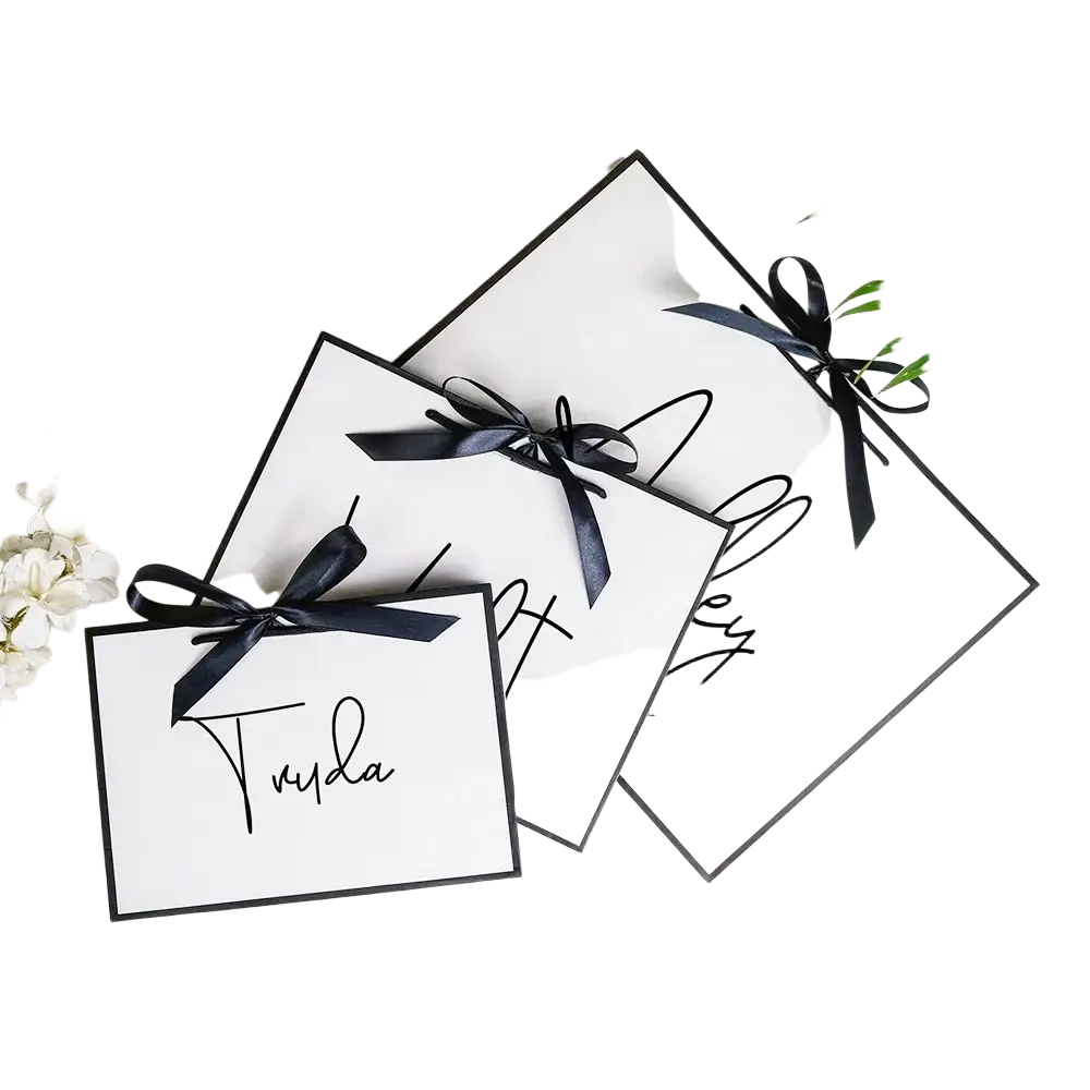 White rectangular personalized bridesmaid gift tags with black cursive script and satin ribbon ties