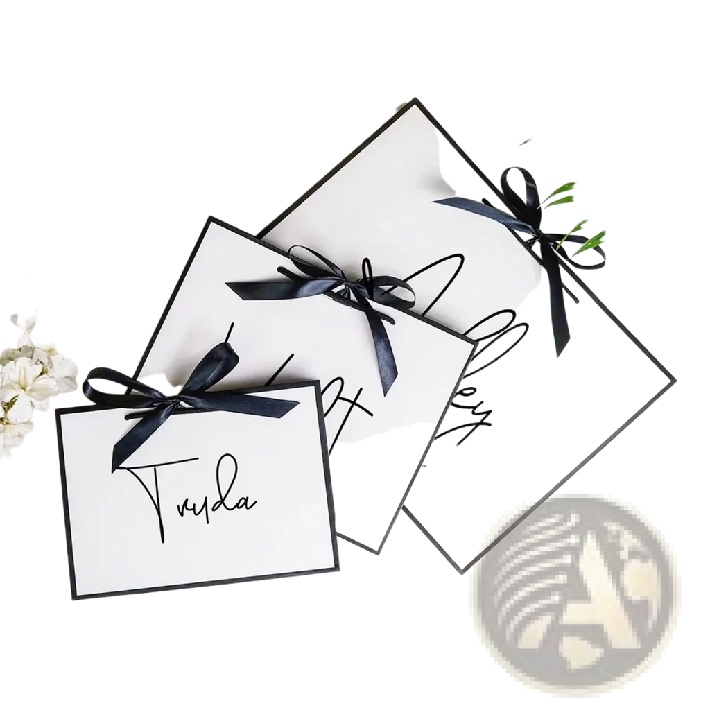 White rectangular personalized bridesmaid gift tags with black cursive script and satin ribbon ties