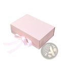 A soft pink personalized bridesmaid proposal gift box with a matching satin ribbon tied into a bow on its side