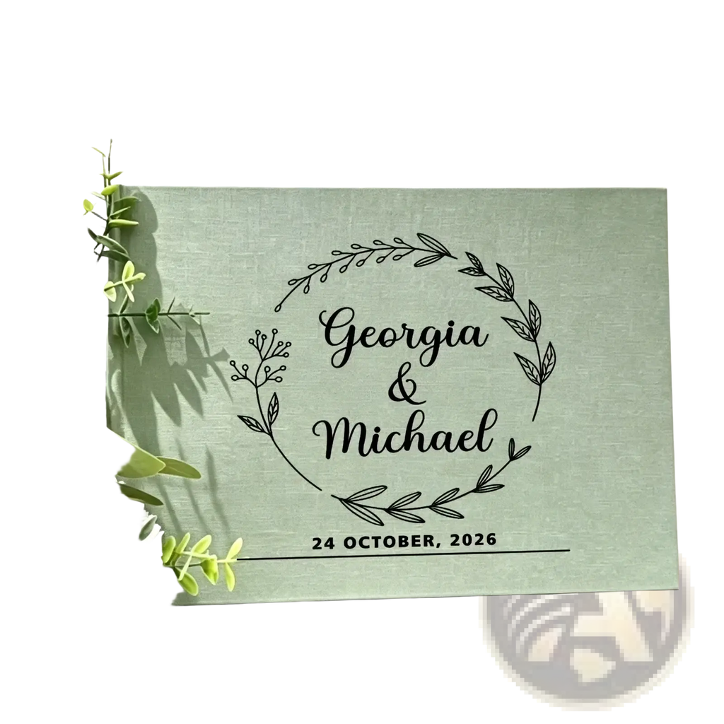 A mint green linen wedding guest book with black engraved floral wreath and personalized names and wedding date