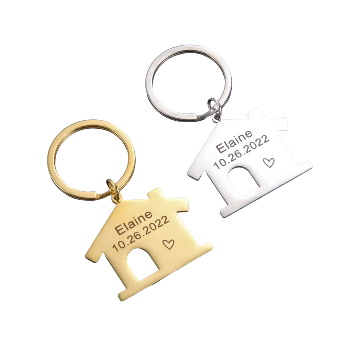 Two personalized house keychains in gold and silver engraved with the name elaine date 10.26.2022 and a heart symbol