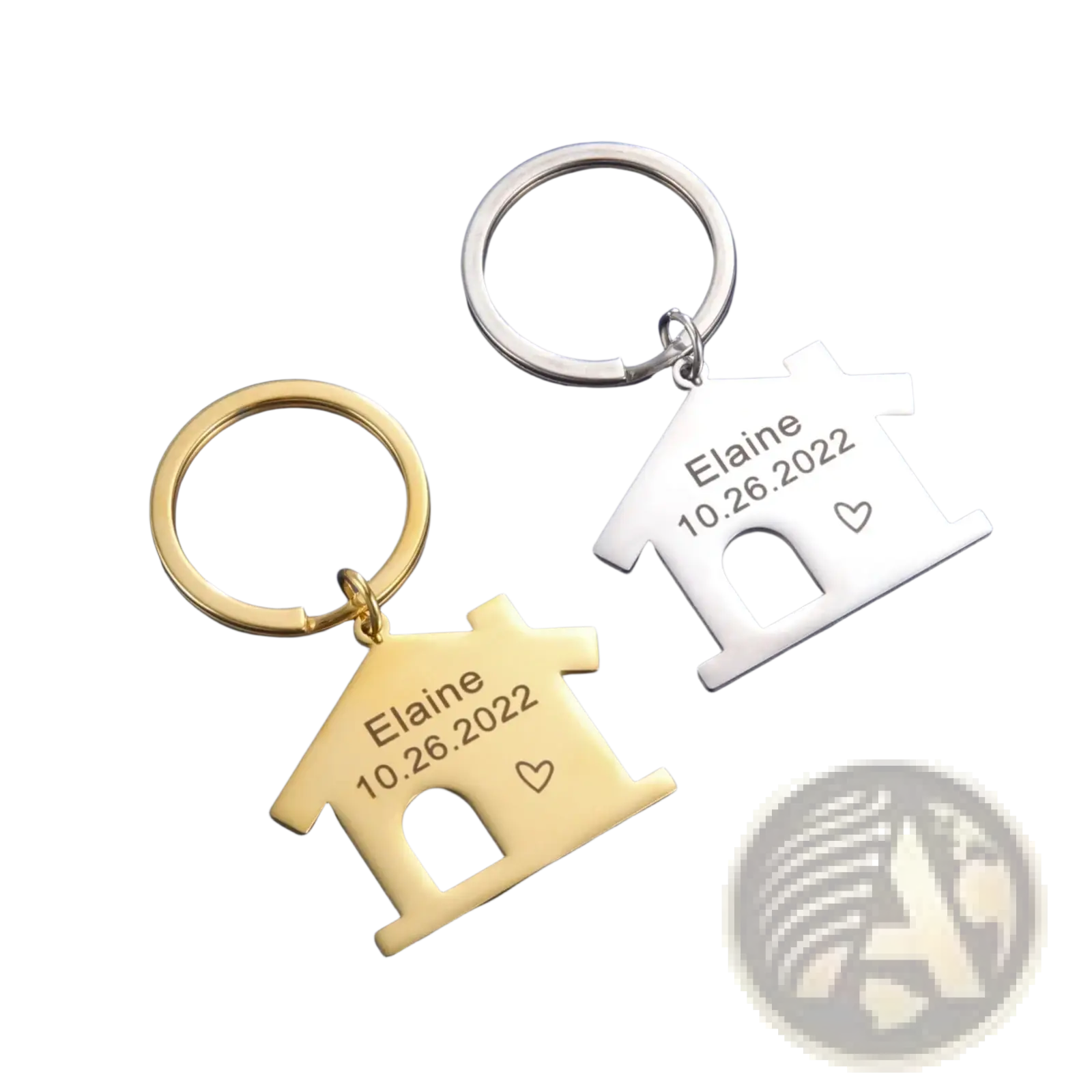 Two personalized house keychains in gold and silver engraved with the name elaine date 10.26.2022 and a heart symbol