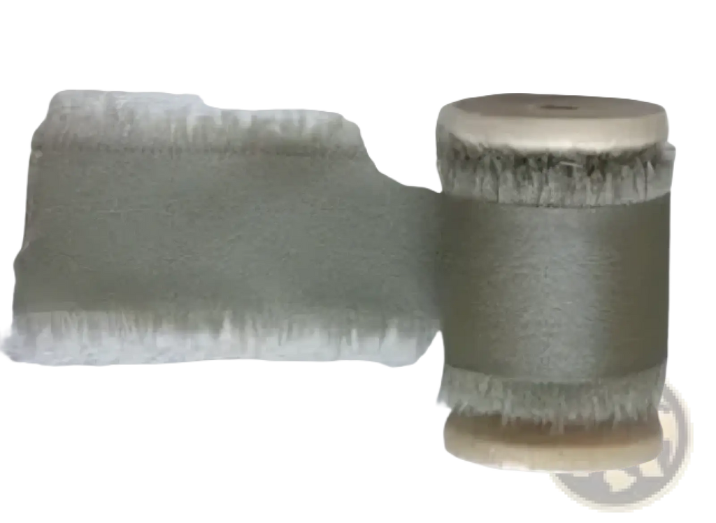 Sage-colored frayed-edge ribbon wound on a spool for personalized minimalist wedding letter books set packaging