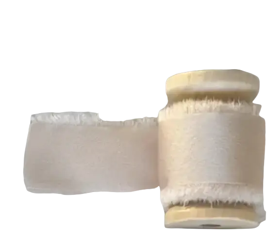 A spool of champagne-colored textured ribbon with frayed edge for personalized minimalist wedding letter books set