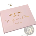 Personalized pink wedding guest book with gold foil lettering and elegant script design including a pen