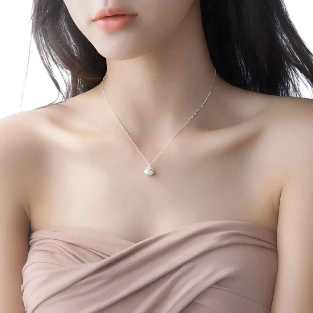 A delicate s925 silver chain necklace with a small sparkling silver shell pendant and pearl detail