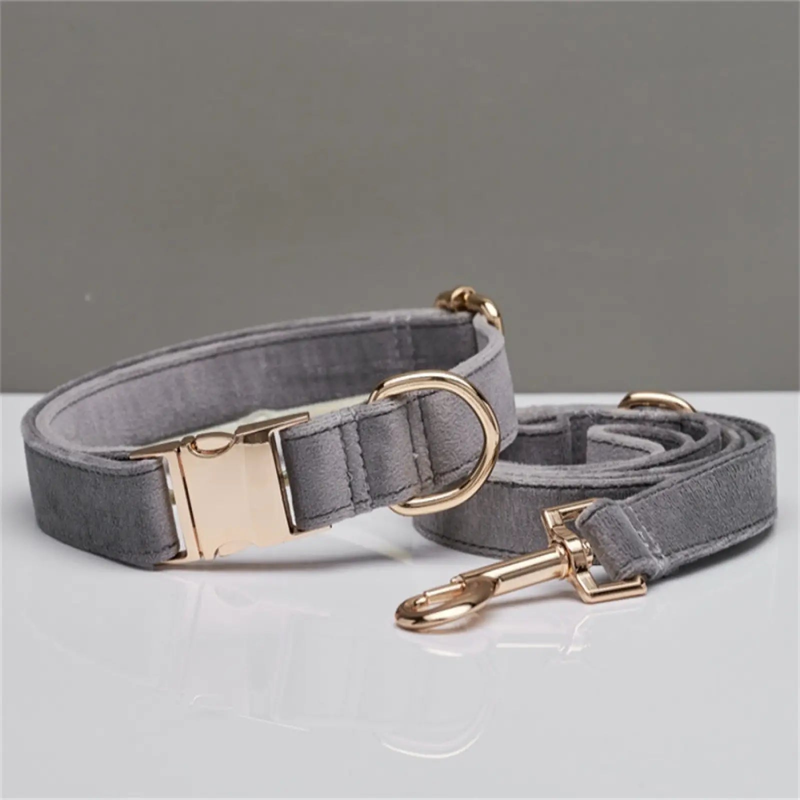 Personalized gray suede dog collar and leash set with gold-tone hardware and velvet bow for stylish pets