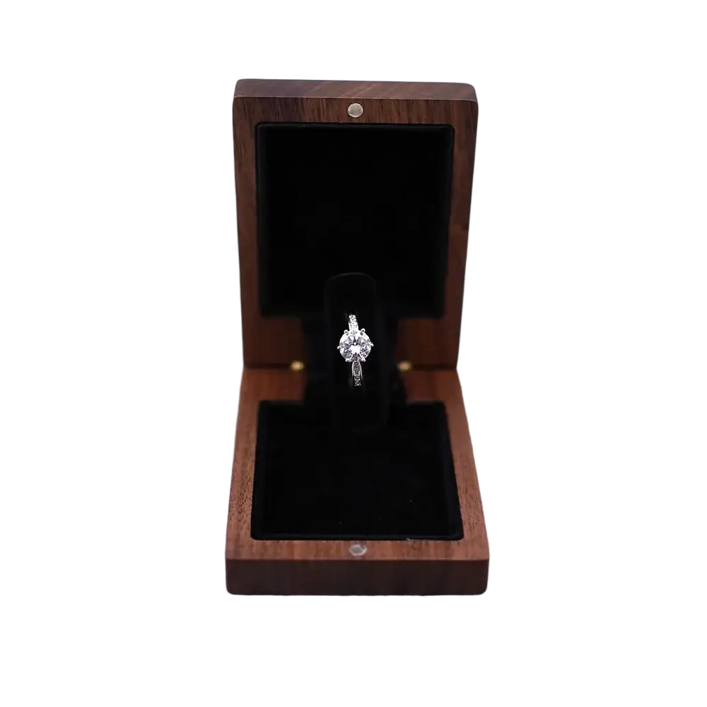 A personalized walnut wood wedding ring box displaying a sparkling diamond engagement ring with a silver band