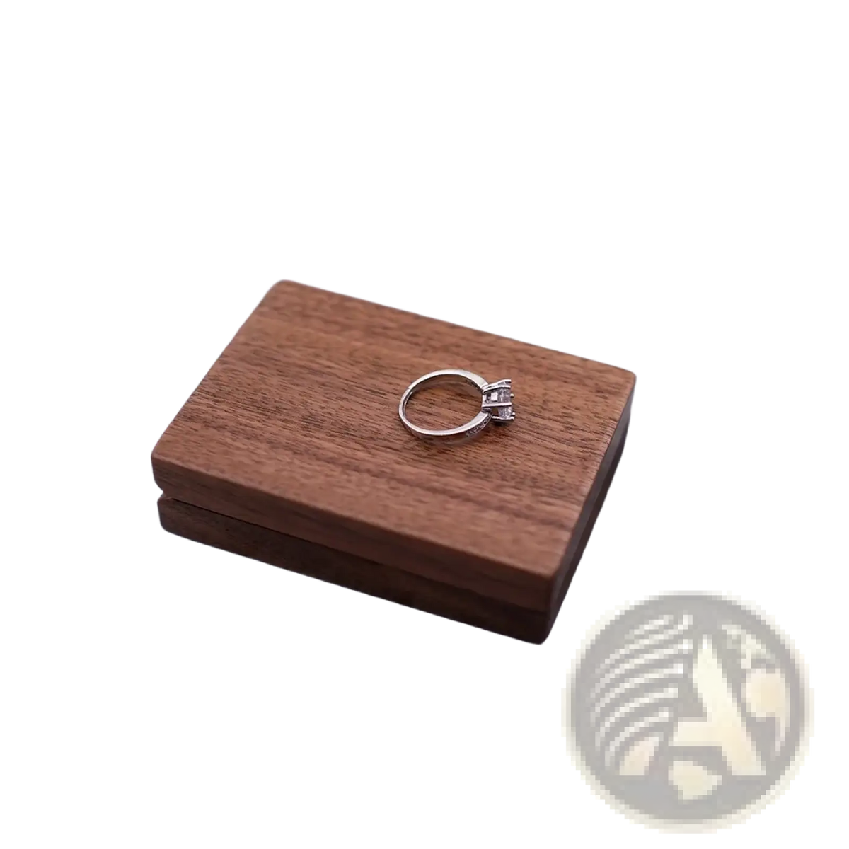 A silver engagement ring with diamonds resting on a personalized walnut wood wedding ring display box